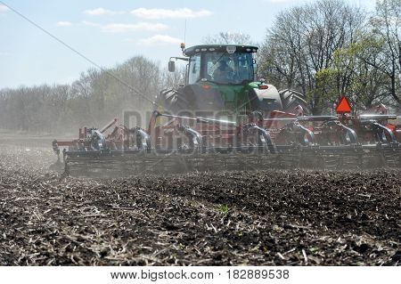 Kharkiv Ukraine - April 13 2017: Tractor with trailed planter working in field in a sunny spring day in Kharkiv Oblast Ukraine on April 13 2017