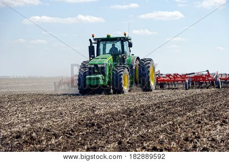 Kharkiv Ukraine - April 13 2017: Tractor with trailed planter working in field in a sunny spring day in Kharkiv Oblast Ukraine on April 13 2017