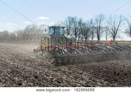 Kharkiv Ukraine - April 13 2017: Tractor with trailed planter working in field in a sunny spring day in Kharkiv Oblast Ukraine on April 13 2017