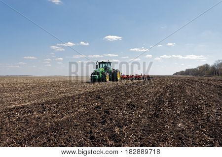 Kharkiv Ukraine - April 13 2017: Tractor with trailed planter working in field in a sunny spring day in Kharkiv Oblast Ukraine on April 13 2017