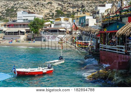 MATALA, GREECE - JUNE 2016: People have a rest at sea bay of Matala town with beautiful beach and taverns around it located on Crete island, Greece