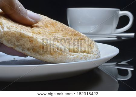 Hand is picking whole grain bread on a white plate.