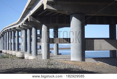 Cement pilings under architecturally beautiful bridge over bay