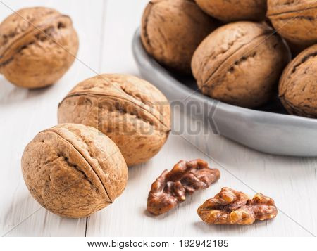 Close up view on inshell walnut on white wooden background