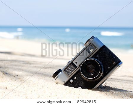 Close-up of a retro camera on the beach. Selective focus