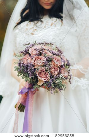 Bride in white dress holding a beautiful wedding bouquet in hands
