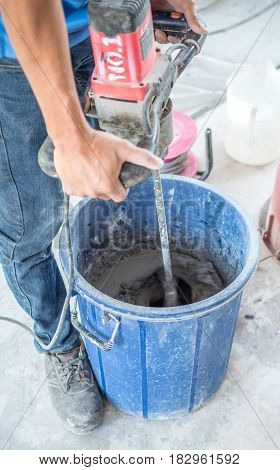Worker are mixed dry mortar with water in the bucket