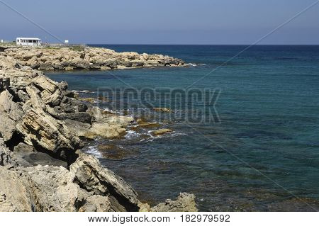 Eroded volcano stone at the beach and clear blue water and blue sky outside the village Lapta in the North of Cyprus