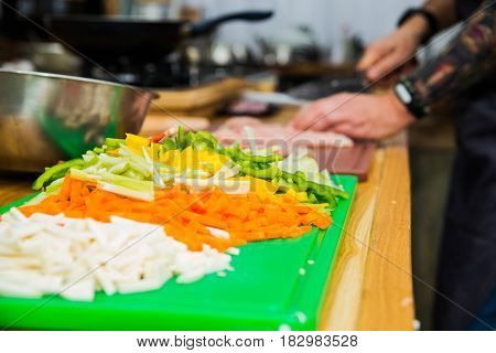 The chef in the kitchen prepares healthy food with vegetables.