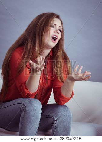 Angry, Pissed Off Young Woman. Attractive Female With Long Brown Hair Sitting On Sofa Being Mad And 