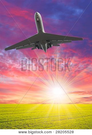 Airliner over the spring meadows against beautiful sunset. Travel concept - last minute metaphor.