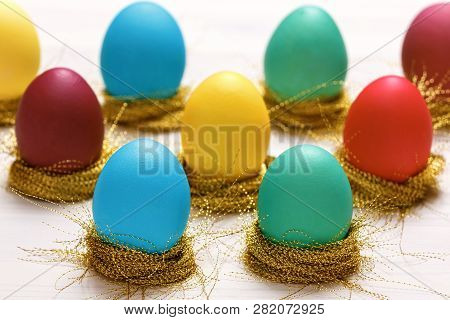 Multi-colored Easter Eggs In Nests Of Shiny Gold Threads