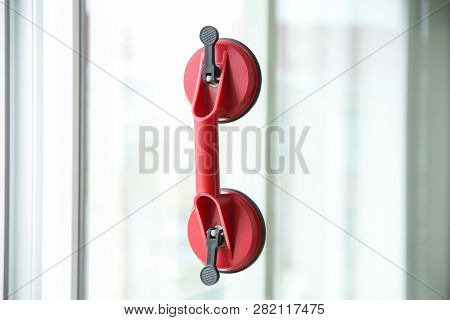 Suction Lifter On Glass Against Blurred Background. Window Installation