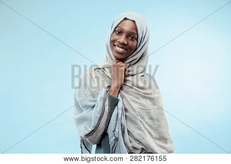 The Beautiful Young Black African Muslim Girl Wearing Gray Hijab At Blue Studio. She Standing With A