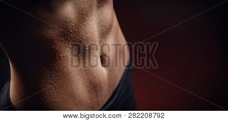 Closeup Of Drop Of Sweat On Skin Abdomen Woman After Workout. Dark Background.