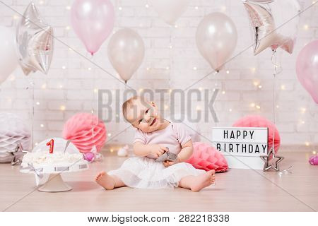 First Birthday Concept - Funny Dirty Girl And Smashed Birthday Cake Over Brick Wall With Lights And 