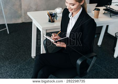 Beautiful Businesswoman Smiling And Writing In Notebook