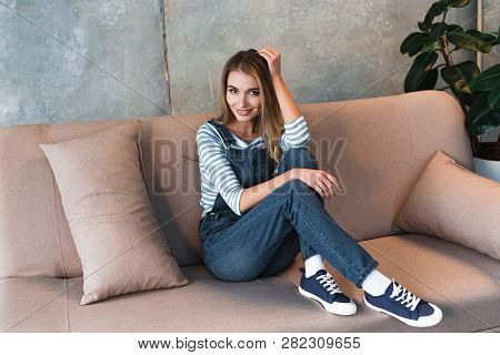 Beautiful Woman Posing And Smiling On Pink Sofa With Pillow