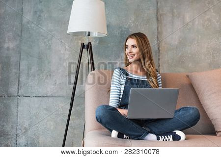 Beautiful Woman Smiling And Sitting On Sofa With Laptop