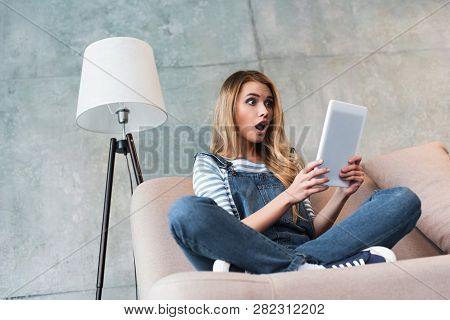 Young Girl Shocked Looking At Digital Tablet In Room