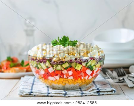 Large Glass Bowl With Crab Salad, Corn, Cucumber And Rice At Table. Layered Crab Sticks And Corn Sal