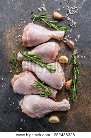 Chicken legs with spices and salt  ready for cooking on cutting board.