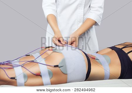 The Procedure Of Myostimulation On The Legs And Buttocks Of A Woman In A Beauty Salon. Caring For Th
