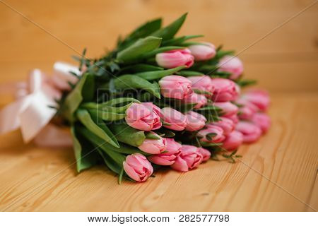Bouquet Of Bright Pink Tulips With A Beautiful Bow On A Wooden Background