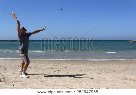 Handsome Mature Man Playing Tennis On The Beach