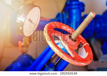 Red gas valve and pressure gauge with an arrow on the limit. Background for gasification. Close up.
