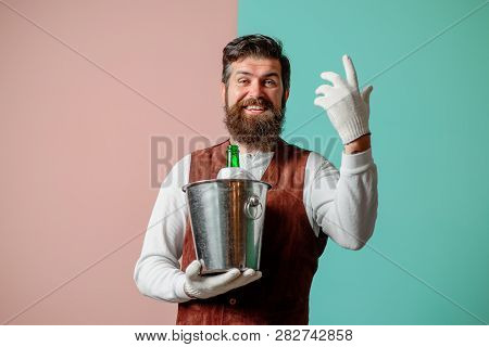 Waiter Holds Wine Cooler With Bottle Of Champagne. Waiter In High Class Restaurant Serving Wine Or C