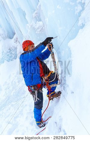 Ice Climber Preraring Running Belay, Screwing Ice Screw Into Glacier Surface
