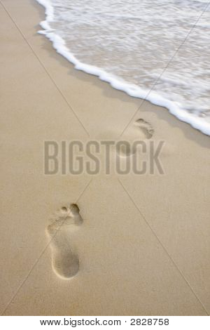 Pegadas na praia e a onda