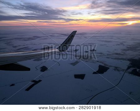 Bucharest, Romania - January 13, 2019 : Wing Of An Airplane Over The Snowy Fields At Sunset. Tarom P
