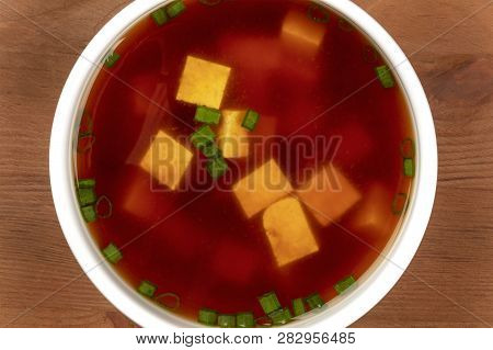 A Closeup Of Miso Shiru Soup With Tofu And Scallions, Shot From The Top On A Dark Rustic Wooden Tabl