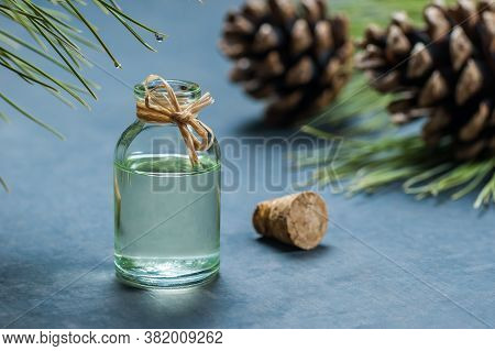 Pine Turpentine Essential Oil In Glass Bottle With Pine Coniferous Leaves And Pine Cone On Rustic Ta