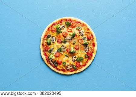 Above View With A Whole Pizza Primavera Isolated On A Blue Colored Background. Vegetarian Pizza With