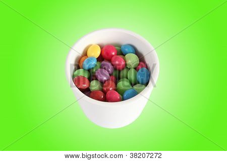 White Jar Full Of Multicolored Candies On Green Gradient