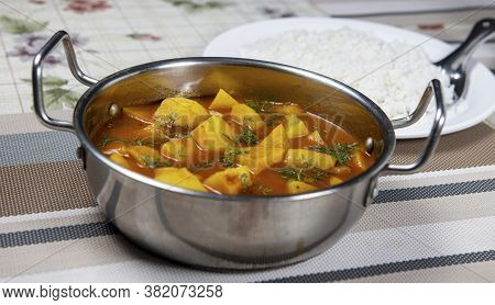 Pot Of Potato Chunks Cooked In Tomato Gravy And Granished With Coriander Leaves. Served Along With S