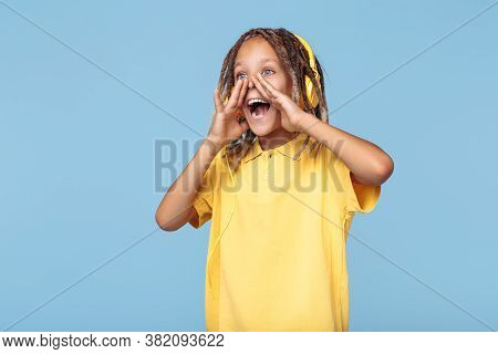 Funny Little Boy With African Dreads Listening Music In Headphones Screaming Over Blue Background.