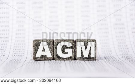 Three Stone Cubes On The Background Of White Financial Statements, Tables With The Word Agm Annual G