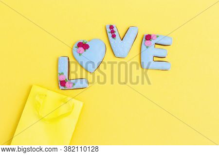 Inscription Love By Homemade Cookies And Yellow Package With Copy Space. Holiday Food Concept. Minim