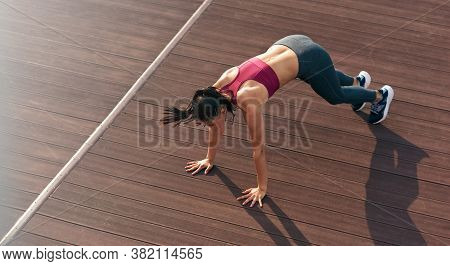 Top View Of A Sporty Woman In Push Up Position Doing Exercises Outdoors. Athlete Girl Doing Fitness 