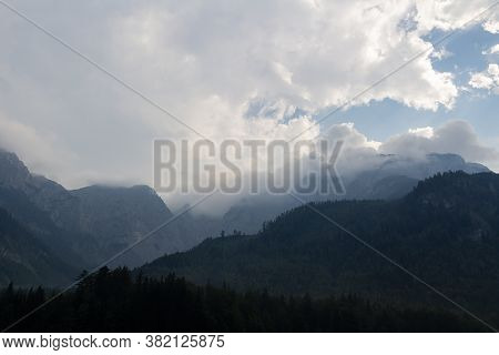Misty Fog After Rain On Austia Alps Mountain Silhouette With Blue Sky