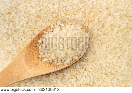 Filled Wooden Spoon With Uncooked Parboiled White Rice. Yellow Golden Grains, Organic Natural Health