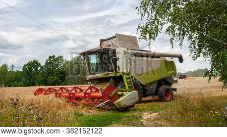 Modern Harvester At Work In The Field During The Wheat Harvesting Season On A Sunny Day. Reaping Mac