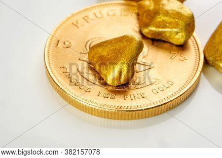 Golden South African Krugerrand One Ounce Coin Laying On A Heap Of Golden Nuggets, Golden Ore On Whi