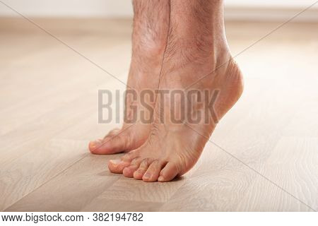 man doing flatfoot correction gymnastic exercise standing on toes at home