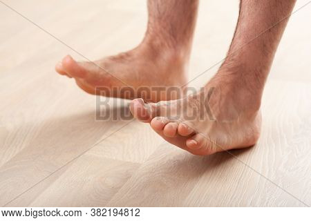 man doing flatfoot correction gymnastic exercise standing on heel at home