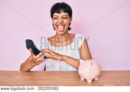 Beautiful brunettte woman caculating money savings sticking tongue out happy with funny expression. 